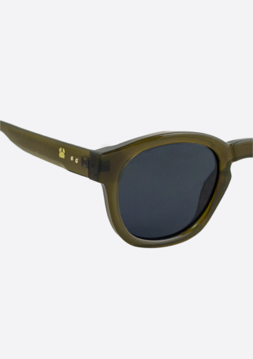 Close-up of Oceanides Atlas Low Green Sunglasses—dark green, oval-shaped unisex frames with black lenses and subtle gold arm detail—shown on a plain white background.