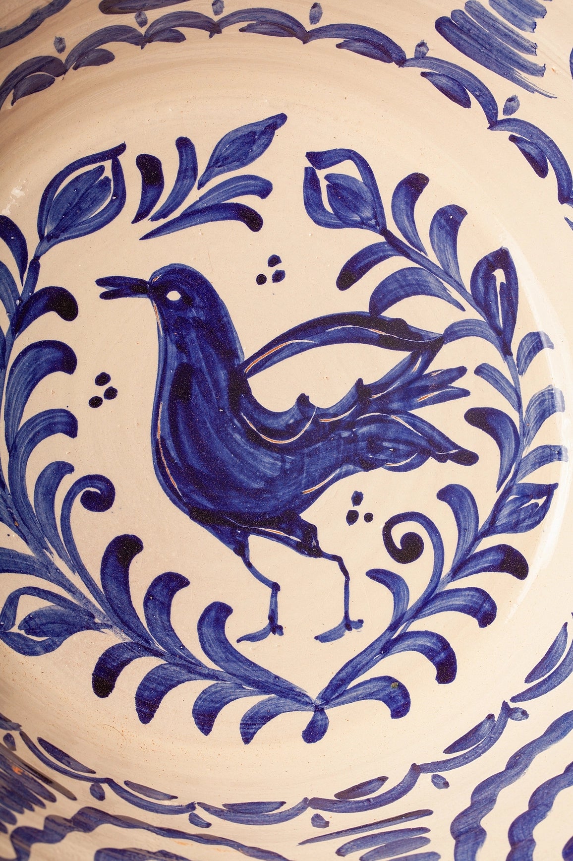 The Blue Lebrillos Granaínos Bowl by Eturel Madrid showcases Andalusian-style hand-painted ceramics, with a blue bird amid leafy branches on a cream background—an ideal match for any handcrafted ceramic plate.