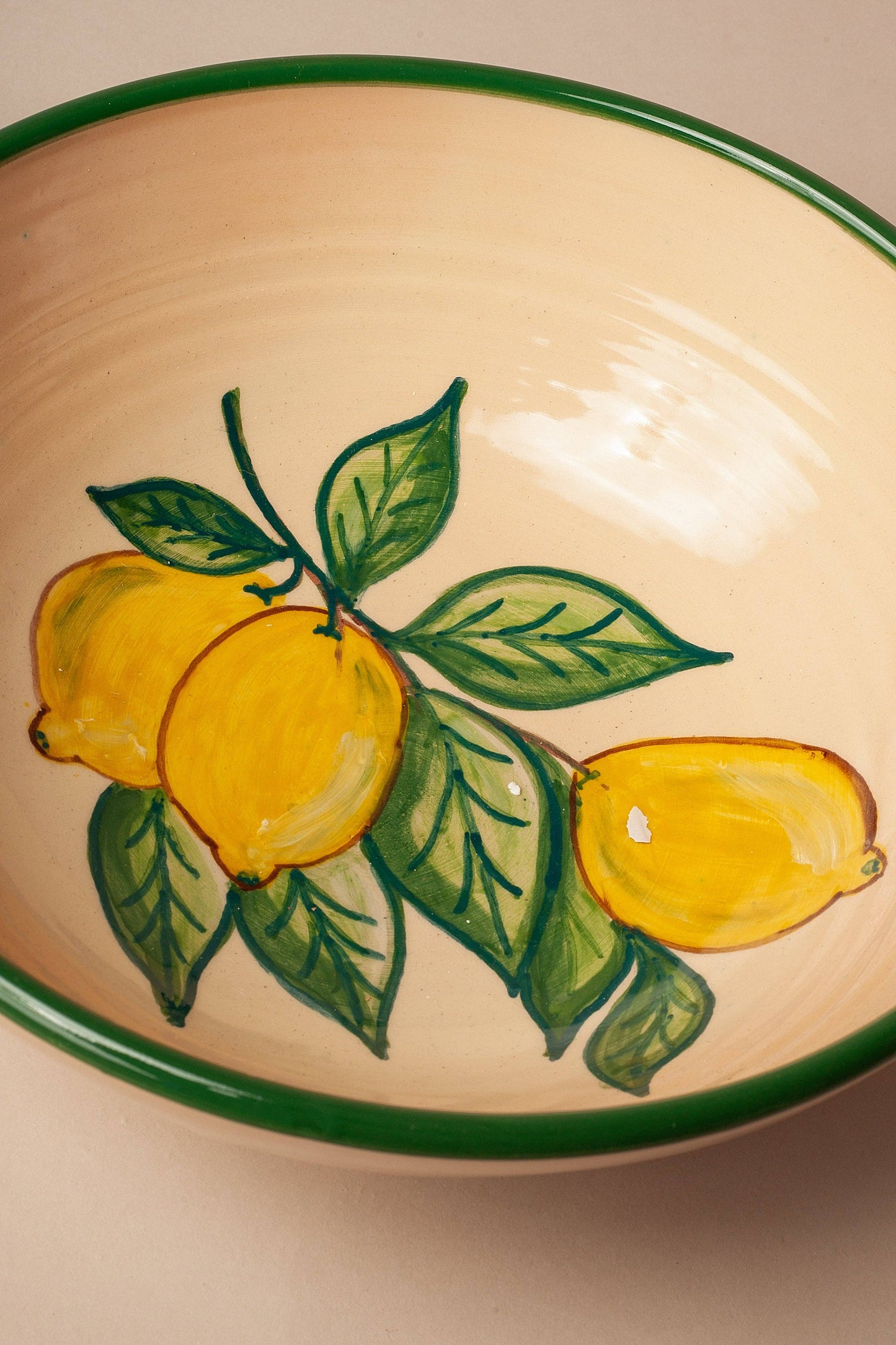 The Huerta Patterned Ceramic Salad Bowl by Eturel Madrid is a handcrafted Córdoba ceramic piece with a green rim, hand-painted inside with three yellow lemons and green leaves for a nature-inspired touch.