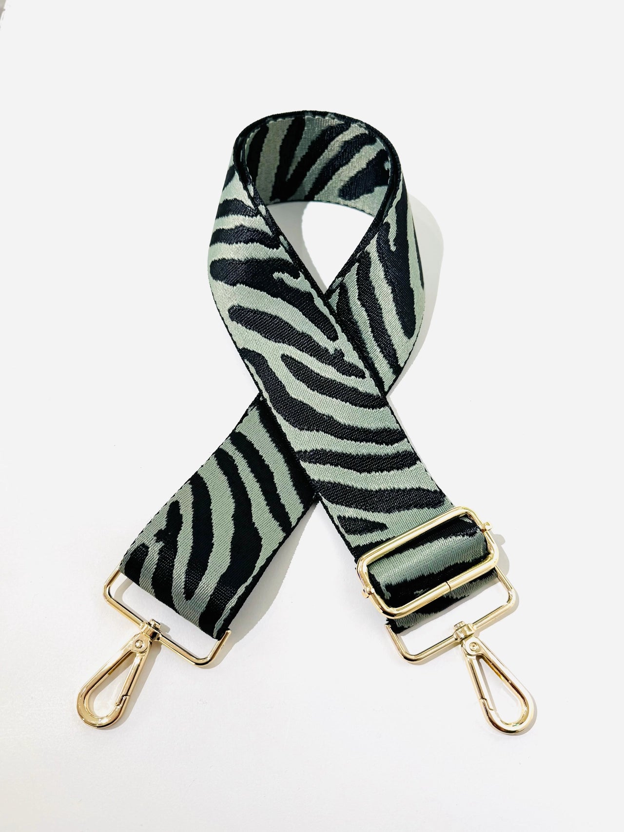 Zebra patterned bag strap with gold hardware on a white background