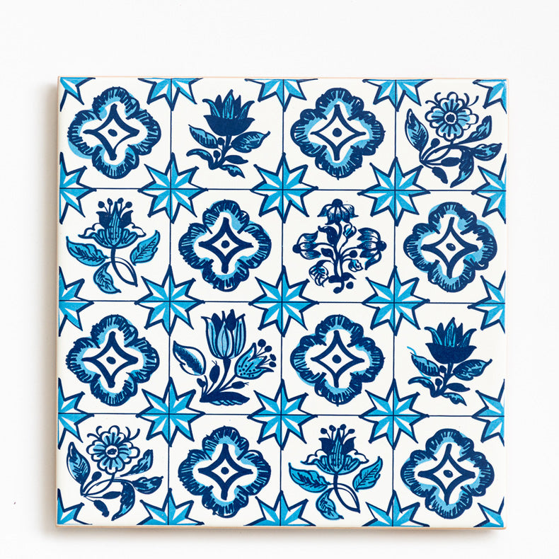 The ObjectoAnonimo Ceramic drinks coaster 11cm - Azulejo 21 features a repeated blue floral and eight-pointed star pattern on white, with dark and light blue shades, creating a vibrant ceramic accent for your table.