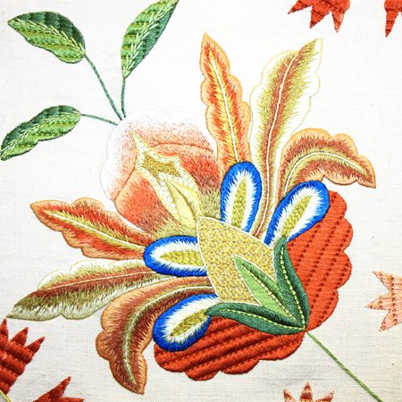 The Terra Lusa Castelo Branco Quilt Notebook features a colorful embroidered flower in orange, yellow, green, and blue on white, showcasing detailed petals and stitching inspired by Portuguese cultural heritage and traditional bedspreads.