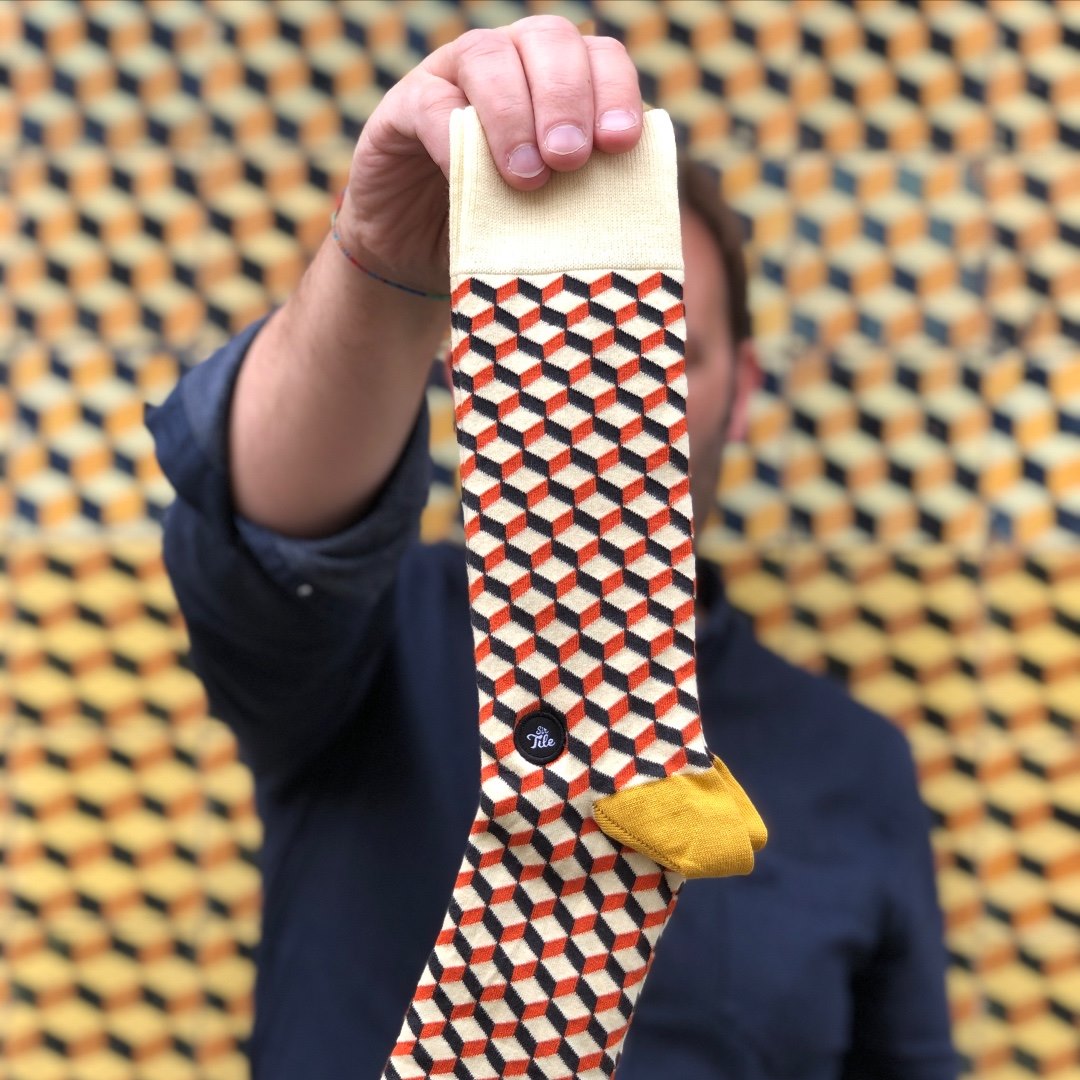 SirTile patterned socks inspired by Portuguese tile design held against geometric azulejo background
