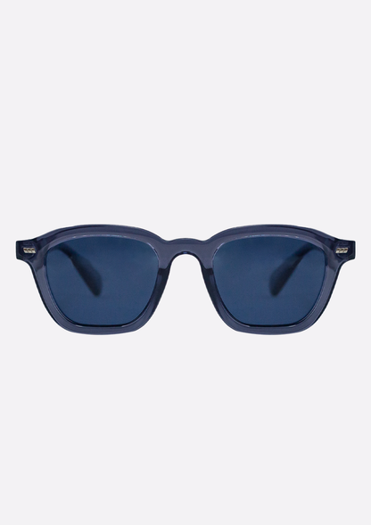 The Oceanides Neda Crystal Blue Sunglasses feature thick recycled plastic frames, dark polarized lenses, and a rectangular shape, shown on a plain light background.