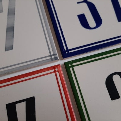 TilePassion Handpainted Ceramic Door Numbers – Custom Portuguese Tiles: Set of four rectangular tiles with colored borders (gray, blue, red, green), each featuring a large partial number and arranged with corners meeting.