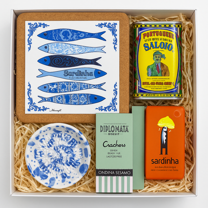 The Iberica Sardine Sampler Kit #1 features Portuguese canned sardines, crackers, a sardine-themed tile, "sardinha" soap, and a blue-and-white ceramic dish on straw-like packing—perfect for a unique cheese board gift.