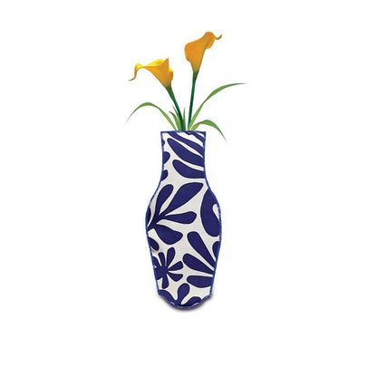 The Barceloning White & Blue Cotton Flower Vase, featuring a white abstract leaf pattern on cobalt blue, holds two yellow calla lilies and green foliage against a white background.