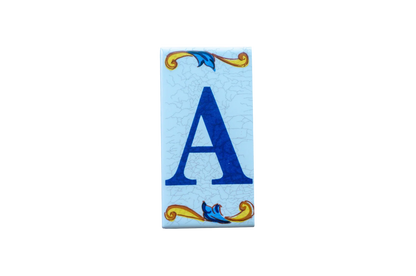 Lisa Croquets Letters – Ceramic House Letter Tiles rectangular Spanish tile, featuring a blue letter A on a light blue background with decorative scrollwork at the top and bottom.