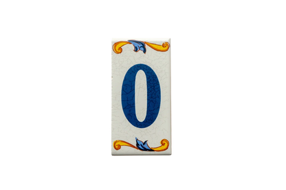Handcrafted in Spain, this rectangular Lisa Croquets Numbers – Ceramic House Number Tile features the number zero in blue, accented by decorative yellow and blue scrollwork at the top and bottom.