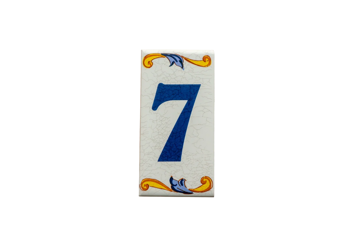 Lisa Croquets Numbers – Ceramic House Number Tiles from LVR Ceramics feature a rectangular shape with a blue number 7 and decorative yellow and blue scrolls at the top and bottom, handcrafted in Spain.