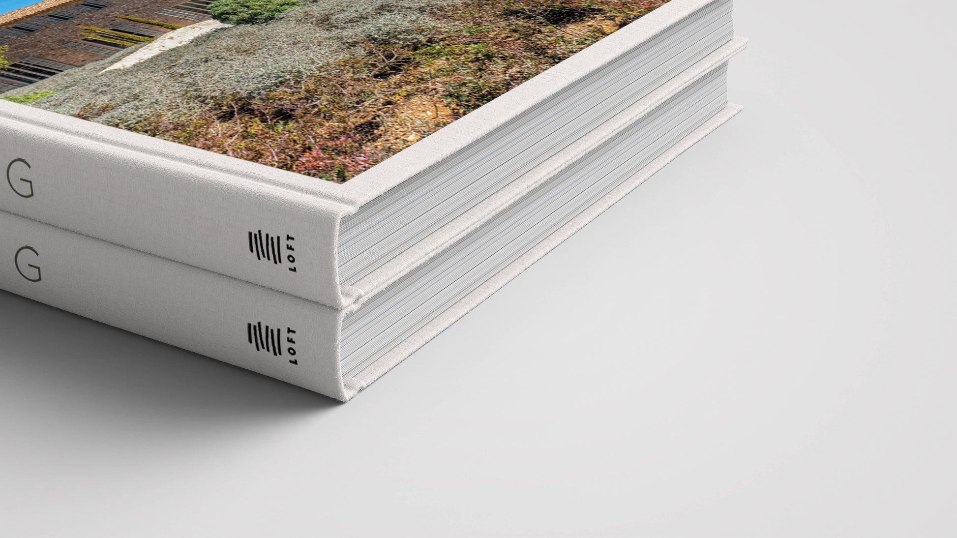 Two hardcover coffee table books with white spines are stacked on a white surface. The top book, "Mallorca Living" by Loft Publications, displays a landscape photo and minimalist black text inspired by Mallorca architecture.