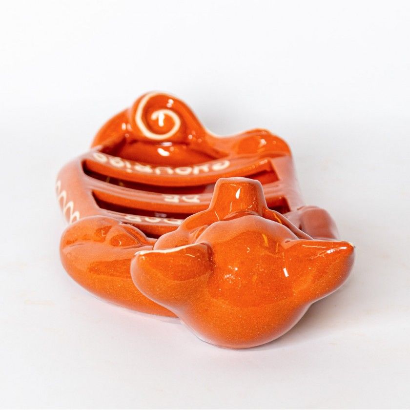 The Ceramica Picas Terracotta Chorizo Pig Roaster is a glossy orange ceramic dish with a curved tail and side fins, inspired by traditional Portuguese designs, displayed on a plain white background.